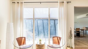 Ein modernes Wohnzimmer mit großem Fenster, zwei Ledersesseln, einem kleinen runden Tisch und einer Kakteenpflanze.