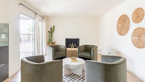 Ein modernes Wohnzimmer mit Kamin, zwei Sesseln, einem Couchtisch und einem großen Fenster.
