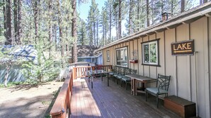 A wooden deck with outdoor seating, surrounded by tall trees.