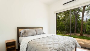 Una camera da letto con un letto grande, un comodino e una finestra vista alberi.