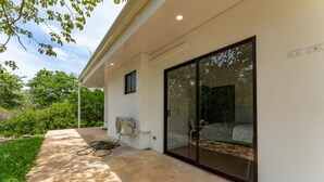 Una casa moderna con un'ampia porta a vetri scorrevoli, una piccola finestra e un condizionatore d'aria.
