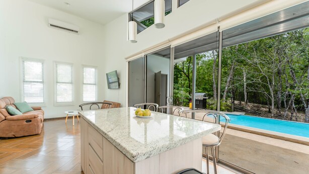 Una cucina moderna con un'isola grande, un'area pranzo e vista su una piscina.