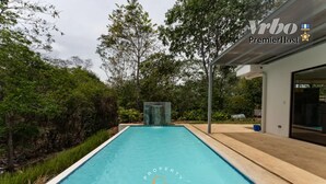 Una casa moderna con piscina, circondata da un lussureggiante verde.