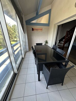 Enjoy dining al fresco in this stylish outdoor space with a glass-top table and wicker chairs.