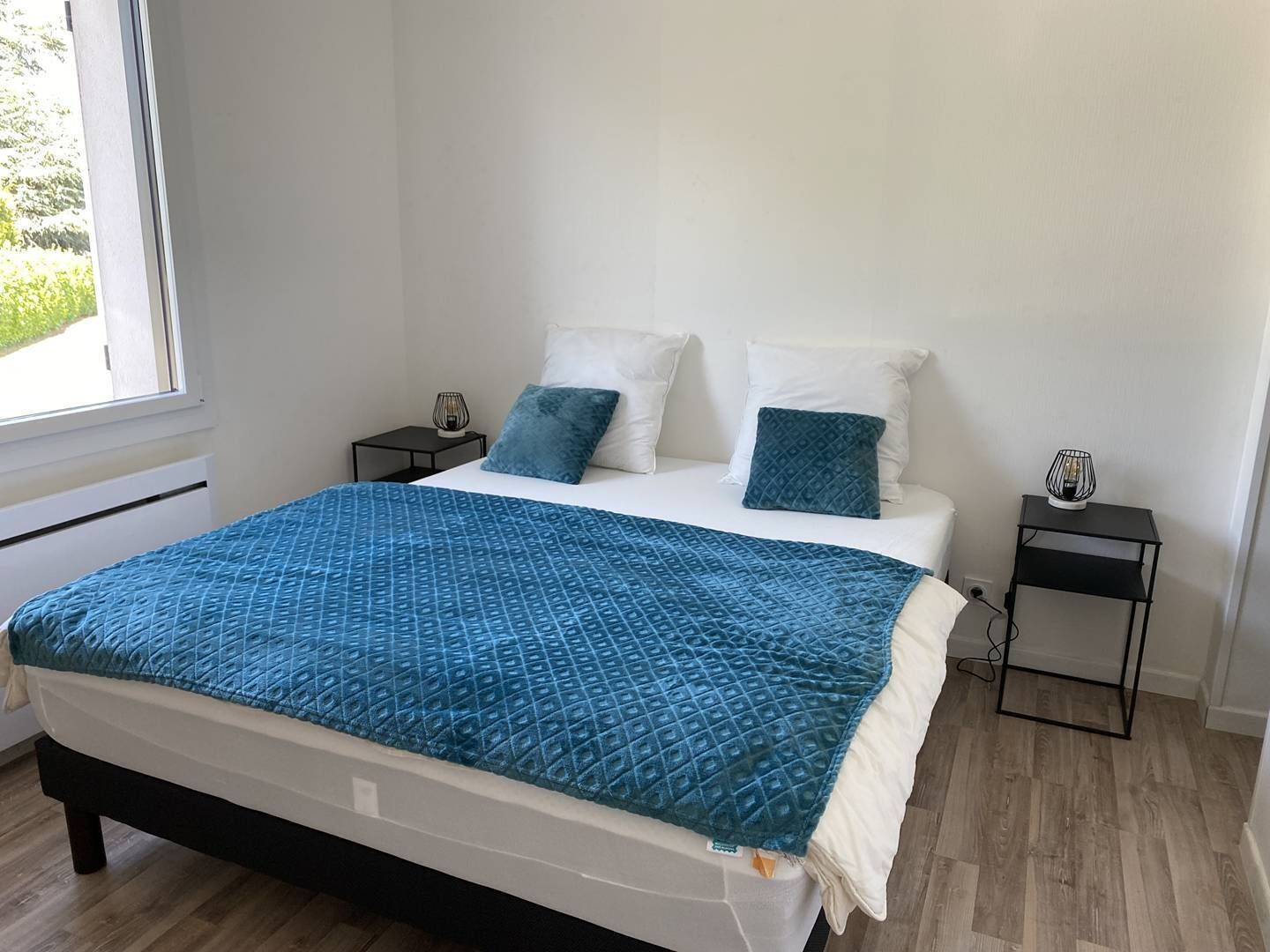 Un dormitorio con cama, dos mesitas de noche, una ventana y vistas al exterior.
