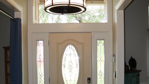 A foyer with a patterned rug, a door with stained glass panels, and a hanging light fixture. - A Little Southwest in the Southeast! Great Pool Home in Jacksonville! (Jacksonville)