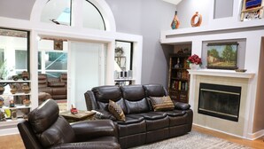 A living room with a leather sofa, a fireplace, and a bookshelf. - A Little Southwest in the Southeast! Great Pool Home in Jacksonville! (Jacksonville)