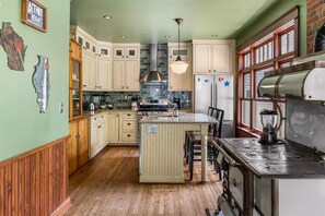 Une cuisine avec des meubles en bois, un îlot central, une cuisinière et un réfrigérateur.