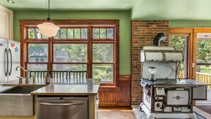 Una cocina con un ventanal grande, una estufa de estilo antiguo y un lavavajillas moderno.