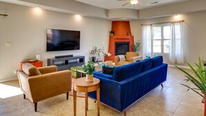 A living room with a blue sofa, a brown armchair, a television, and a fireplace. - Pet-Friendly Albuquerque Vacation Escape! (Albuquerque)