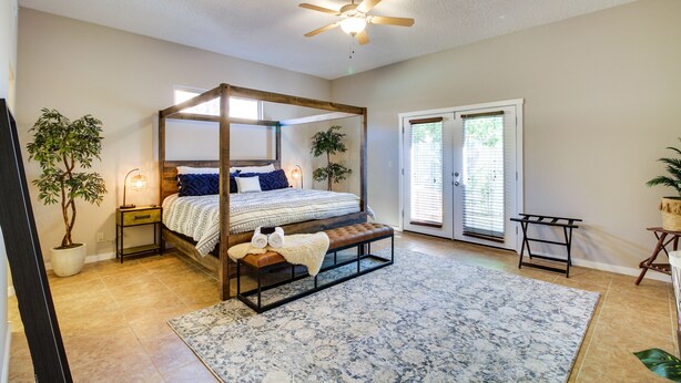 A four-poster bed with a bench, a ceiling fan, and a large window with blinds. - Pet-Friendly Albuquerque Vacation Escape! (Albuquerque)