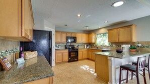 A kitchen with wooden cabinets, a black refrigerator, a microwave, and a granite countertop. - Pet-Friendly Albuquerque Vacation Escape! (Albuquerque)