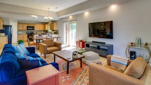 A modern living room with a sofa, coffee table, and ottoman. There is a kitchen in the background with cabinets and a microwave. - Pet-Friendly Albuquerque Vacation Escape! (Albuquerque)