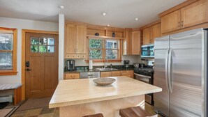 Una cocina moderna con armarios de madera, un refrigerador de acero inoxidable y una isla grande con un bol.