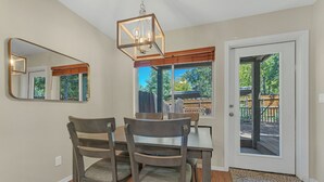 A dining area with a table and chairs, a mirror, and a door leading to an outdoor deck.