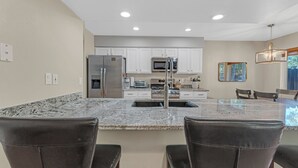 A modern kitchen with white cabinets, stainless steel appliances, and a granite countertop.