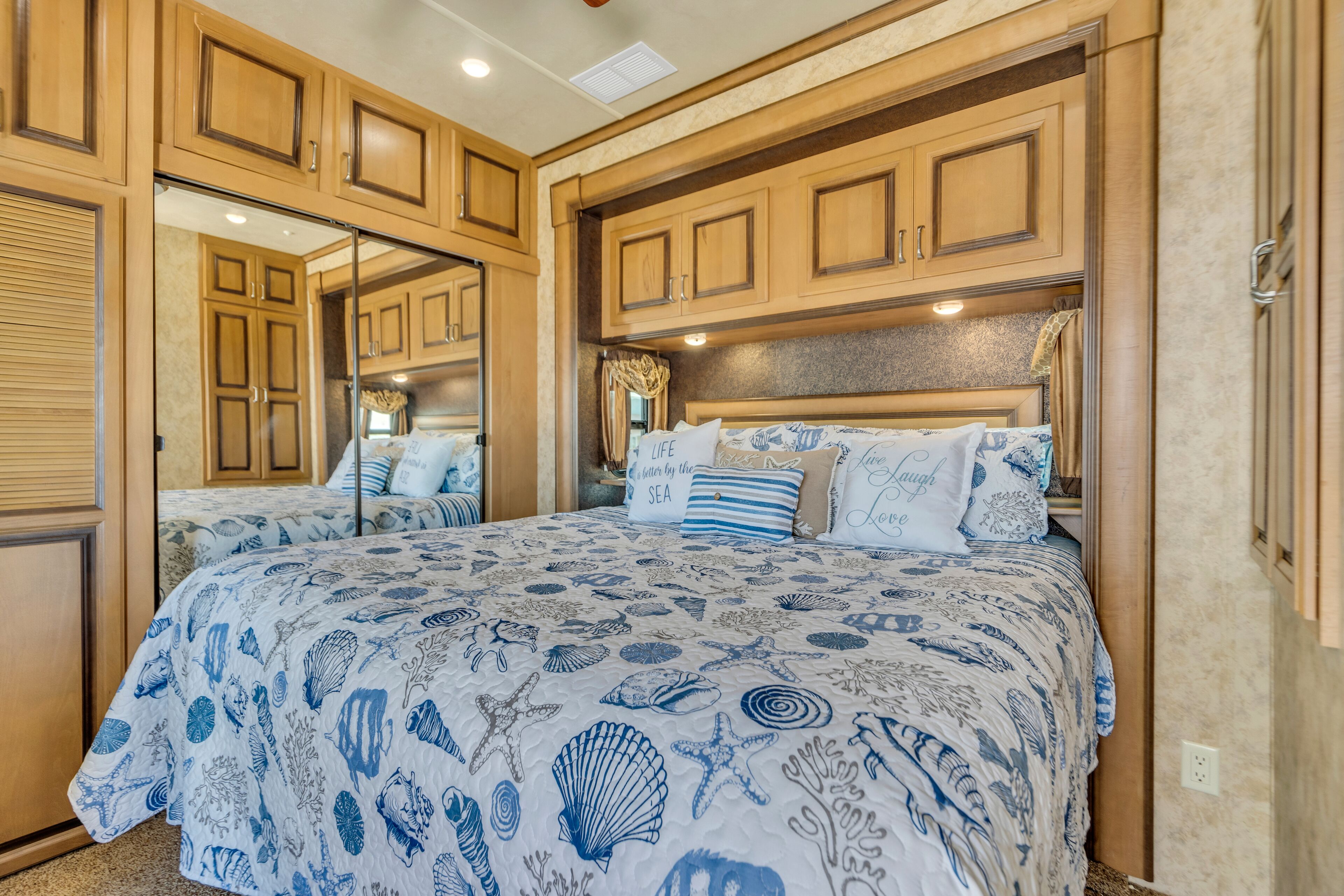A bedroom with a large bed, wooden cabinets, and a mirrored closet door.