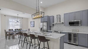 Una cocina moderna con gabinetes grises, electrodomésticos de acero inoxidable y una isla central con taburetes de bar.