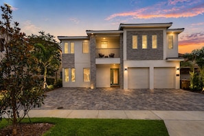 A modern two-story house with a garage, stone accents, and a well-lit entrance.