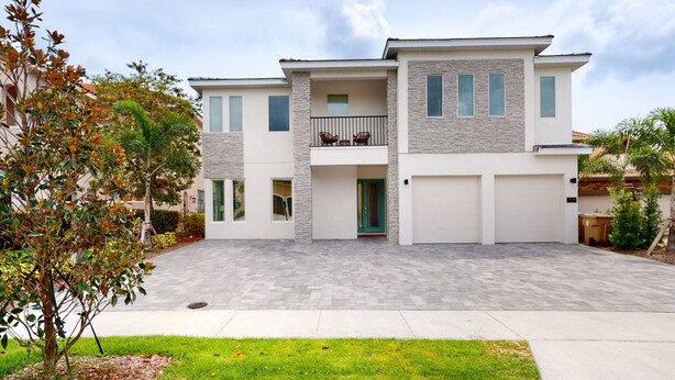 A modern two-story house with a balcony, a garage, and a well-maintained lawn.