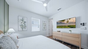 Ein Schlafzimmer mit einem Bett, einem Schminktisch, einem Fernseher und Bildern an der Wand.