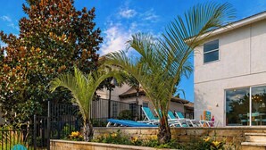 A patio with a fire pit, outdoor seating, and a view of a house with a pool.