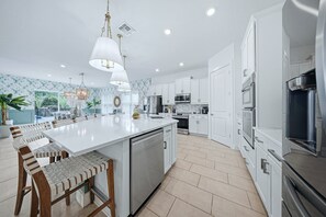 A modern kitchen with white cabinetry, a central island, and pendant lighting.