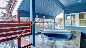 A blue room with a glass shower, a wooden bench, and a window.
