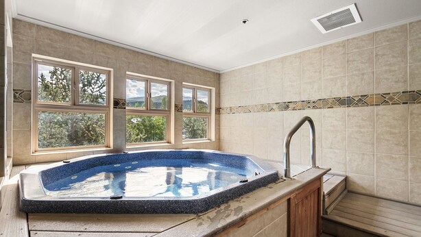 A bathroom with a large bathtub, a window with a view of trees, and a shower area.
