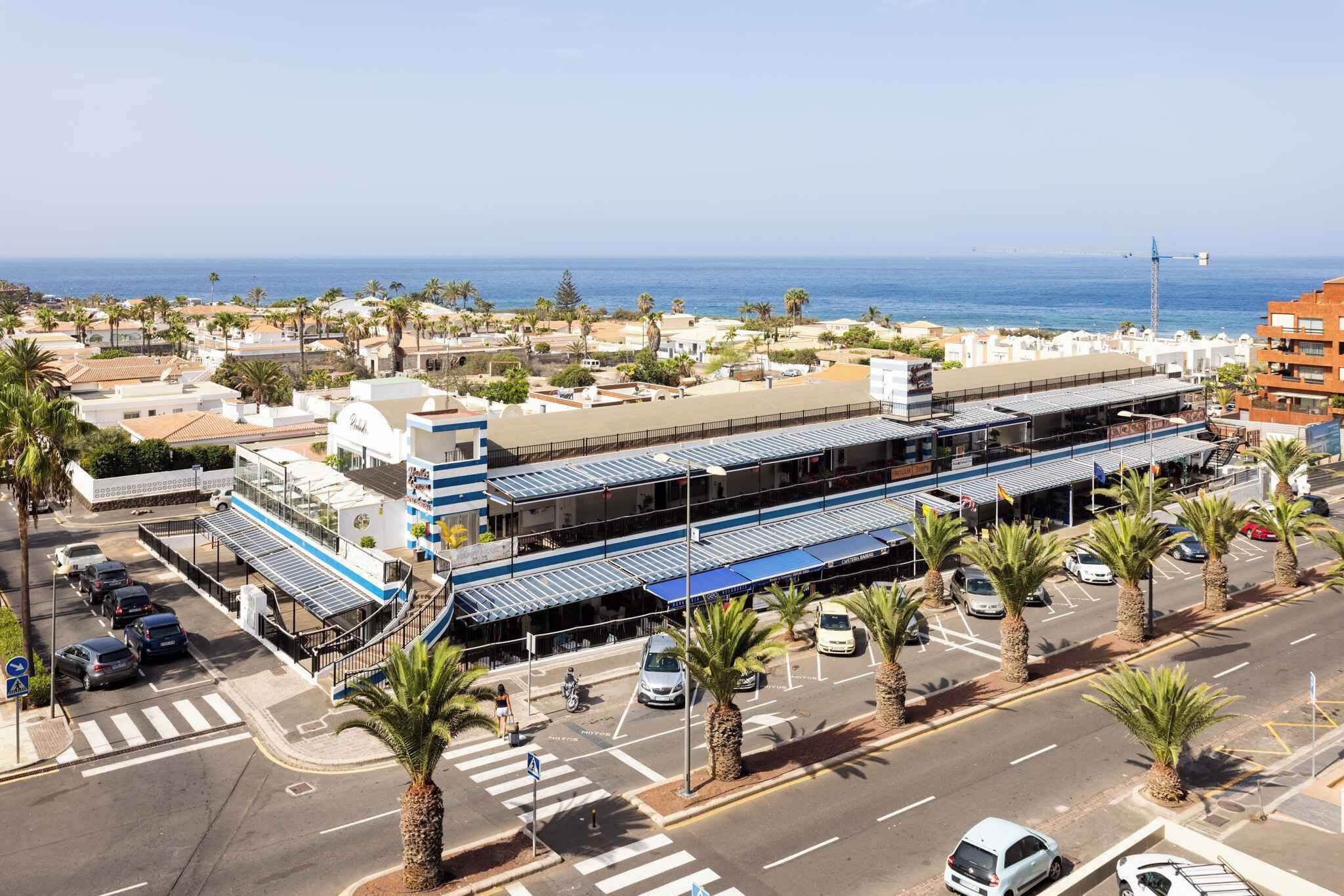 Un hotel costero de diseño moderno, con un atrio central, varios pisos y vistas al mar.