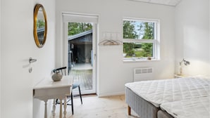 A bedroom with a bed, a desk, a chair, a mirror, and a window with a view of the outdoors. - 3 bedroom pet friendly home in Græsted (Græsted)