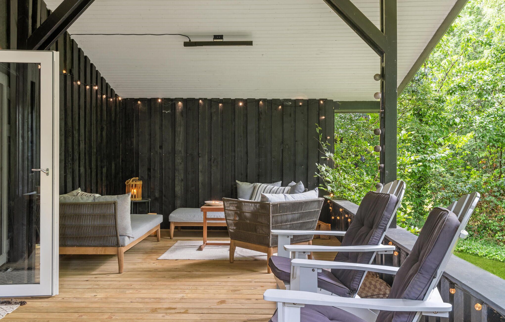 A covered outdoor seating area with wicker furniture and a view of greenery.