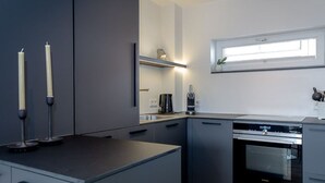 Una cocina moderna con armarios grises, horno empotrado y ventana sobre el fregadero.