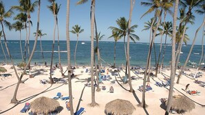 A beach with palm trees, sun loungers, and thatched umbrellas. - Royal Suites of Lifestyle Holiday Resort - All inclusive (Puerto Plata)