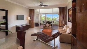 A hotel room with a balcony, a sofa, a recliner, a TV, and a desk. - Royal Suites of Lifestyle Holiday Resort - All inclusive (Puerto Plata)
