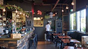 A restaurant interior with a bar area, seating, and a person working at the bar.
