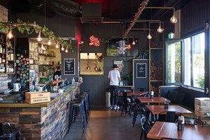 A restaurant interior with a bar area, seating, and a person working at the bar. - Sirius (Kingscliff)