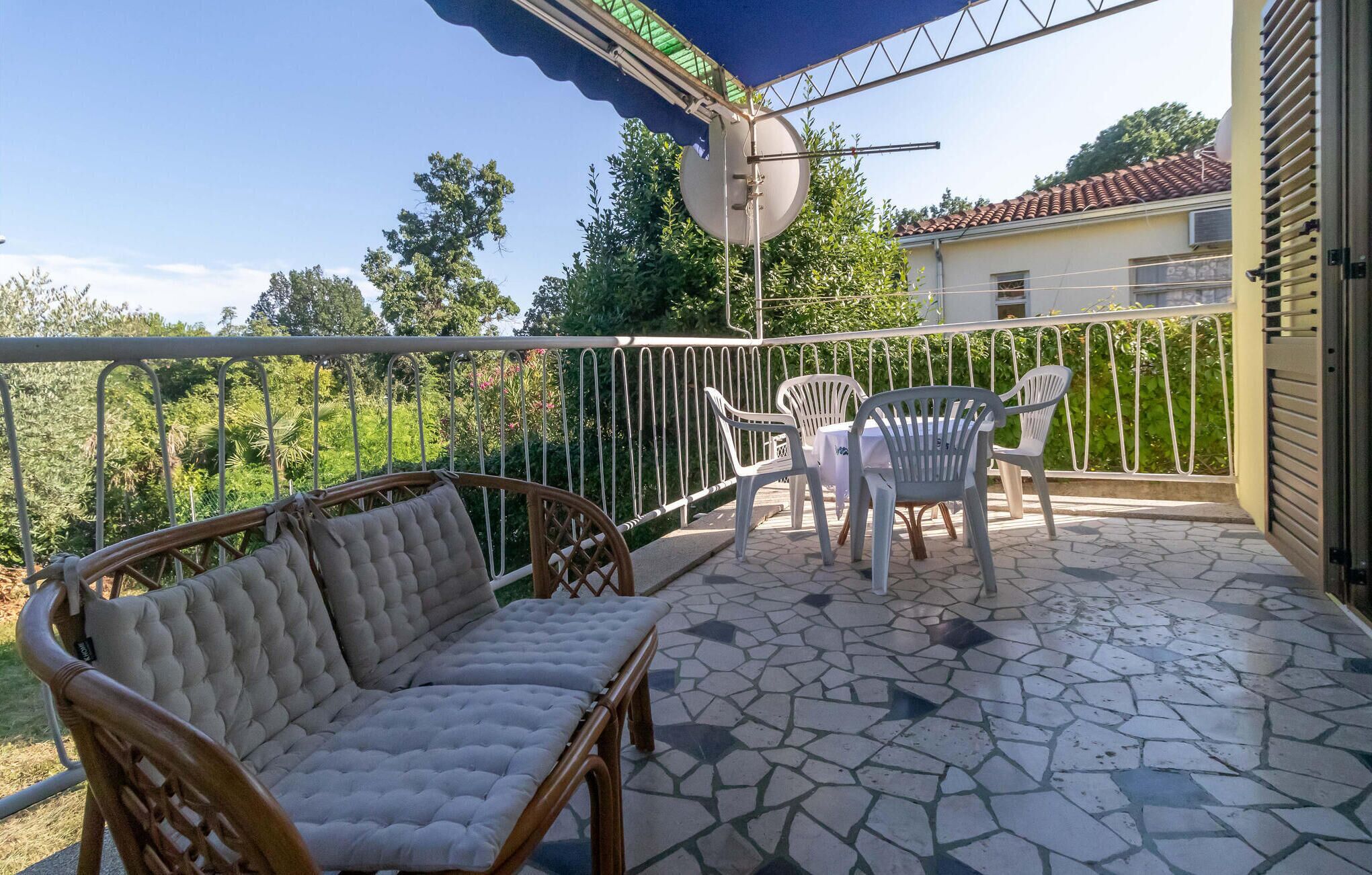 Eine überdachte Terrasse mit einer Couch, Stühlen und einem Tisch.