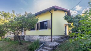 A yellow house with a stone foundation, a red roof, and a small front porch. - 3 bedroom cozy apartment in Ika (Ika)
