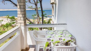 Un balcón con mesa y sillas, con vista a una playa y al mar.