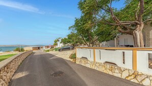 Una carretera costera con un muro de piedra a un lado y un edificio con balcón al otro.