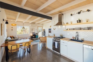 Una cocina moderna con techo de madera, una isla central y un comedor con sillas.