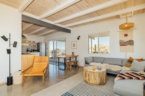 Amplia sala de estar con techo de madera, un sofá, una mesa de comedor y una silla.