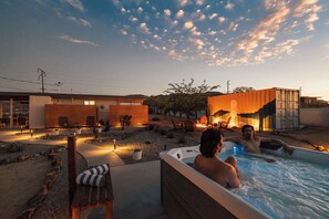 Un área de hidromasaje con piscina, mobiliario exterior y un edificio moderno al fondo.