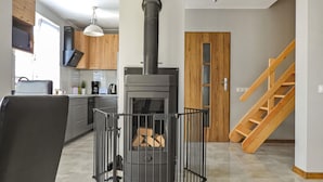 Una cocina moderna con estufa de leña integrada, armarios de madera y una valla de metal negro alrededor de la estufa.