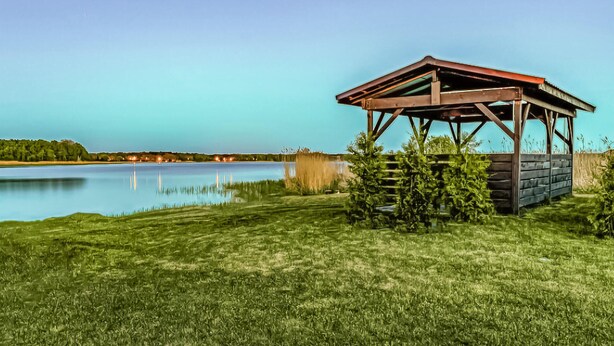 Un quiosco de madera junto a un lago con cielo despejado.