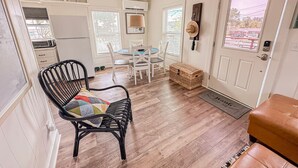 Un espacio habitable compacto con comedor, cocina y una zona de estar con una silla y un banco.