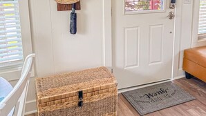 Una puerta blanca con un ventanal, una cesta de mimbre y un tapiz de madera.