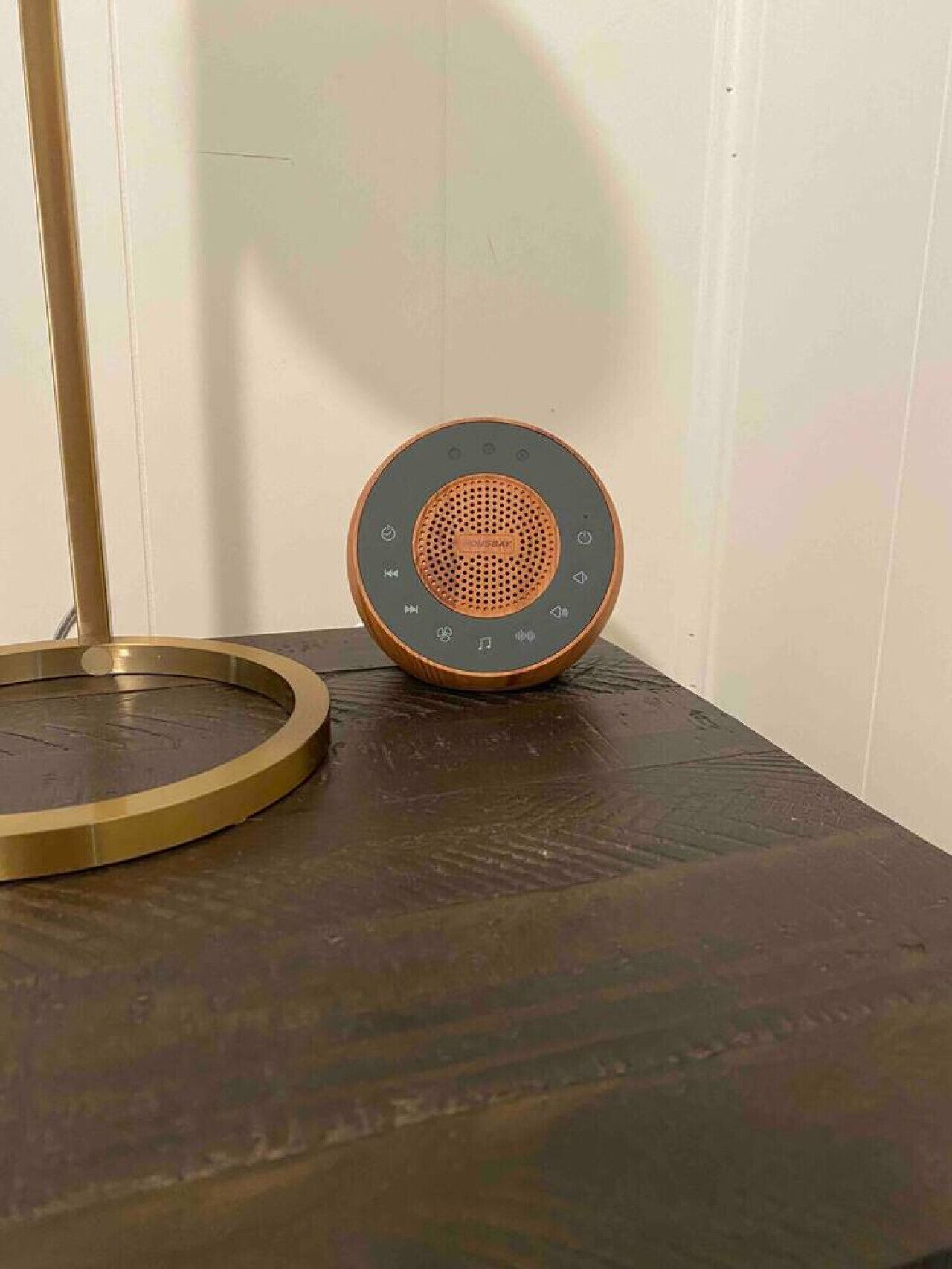 Een speaker op een houten tafel met een metalen voet.