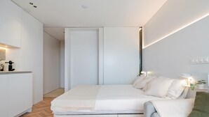 A modern bedroom with a bed, bedside table, and a sofa. - Romantic loft sea views 8km from Port Aventura (La Pineda)